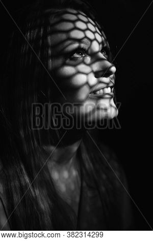 Beautiful woman confesses in the confessional, black and white. Praying woman, fine art portrait with interesting ligth and shadow pattern. Absolution. 