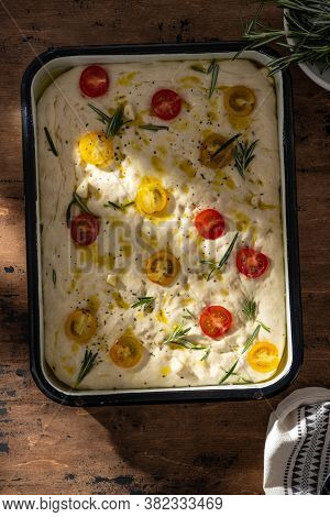 Raw Focaccia Dough In A Baking Dish. Traditional Italian Focaccia With Rosemary, Cherry Tomatoes And