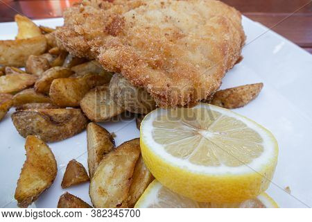 Feldkirch, Austria - July 26, 2020: Breaded Cordon Bleu Steak Served With Baked Potatoes And Lemon