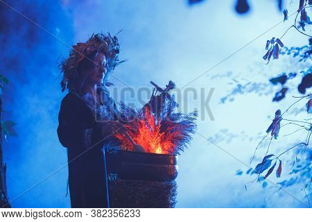 A Forest Witch Brews A Potion Holding A Voodoo Doll.