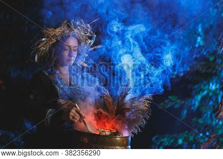 A Forest Witch Brews A Potion Holding A Voodoo Doll.