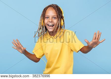 Positive Little Boy With African Dreads Listening Music In Headphones Dancing Over Blue Background.