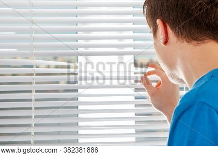 Young Man Next To Jalousie In A Room