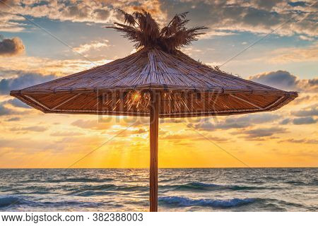 Straw Umbrella On Tropical Sea Beach And Beautiful Sea Sunrise With Dramatic Sky Clouds
