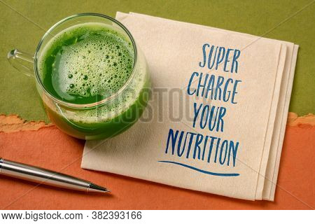 super charge your nutririon inspirational note - handwriting on a napkin with a glass of fresh, green vegetable juice, healthy eating and lifestyle concept