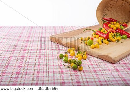 Colorful Peppers Fallen From A Basket On A Table With Checkered Tablecloth And White Background, Sel