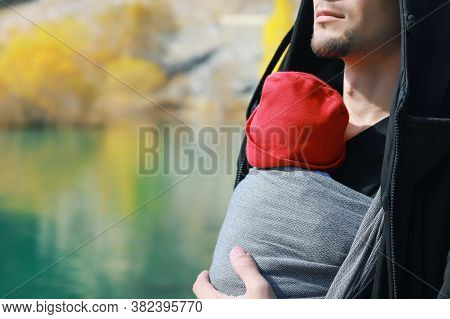 Attractive Young Father With Her Infant Baby In Sling Outdoor. Man Is Carrying Her Child And Travel 