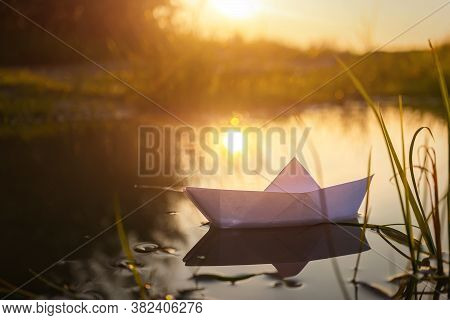 A Paper Boat Floats On The Water At Dawn. Creative Concept Of Outdoor Recreation, River, Travel. Coz