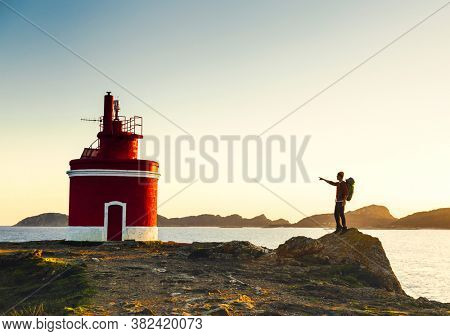 Man pointing to a beautiful ligthouse at sunset 