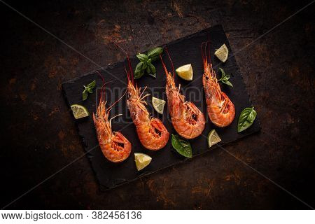 Fresh Uncooked King Prawns On Black Slate Board With Lemon