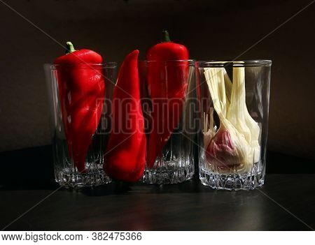 Still Life With Red Ramiro Peppers And Garlic Bulb In The Vintage Glass Beakers Against A Low Key Ba