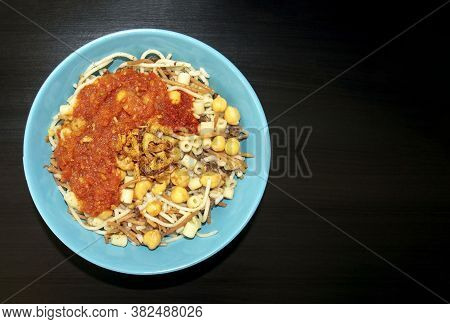 Famous Traditional Arabic, Egyptian Dish - Koshari. National Kushari In A Turquoise Plate On Dark Wo