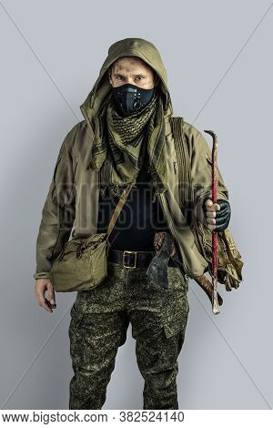 Man With Burglar Crowbar Wearing Black Protactive Face Mask And Jacket With Hood On Gray Background
