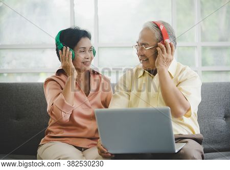 Lovely Elderly Couple Is Watiching And Listening To Romance Music From Laptop Computer With Colorful