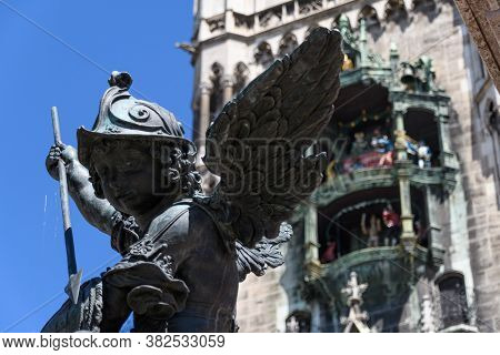 Munich, Germany: Sculpture At The Base Of The Column On Marienplatz. Statue Of A Bronze Putto Killin