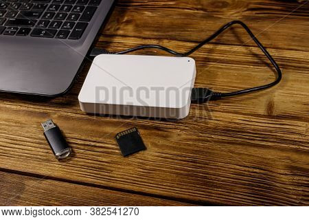 External Hdd Connected To Laptop Computer, Sd Memory Card And Usb Flash Drive On A Wooden Desk. Conc