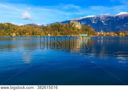 Panorama Of Lake Bled Blejsko Jezero, Slovenis With Boat And Autumn Colorful Julian Alps In Backgrou