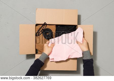 Man Putting Different Clothes In A Carboad Box. Clothes Donation Or Reuse Concept
