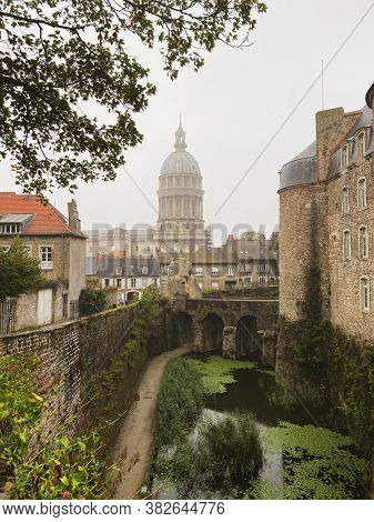 Basilica of Our Lady at the fortified city of Boulogne-sur-Mer, castle in foreground. Cloudy and rainy day with unrecognizable person
