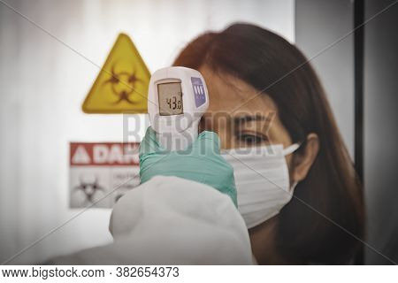 Covid-19 Coronavirus Concept : Hand Of A Female Doctor Uses A Digital Thermometer For A Middle-aged 