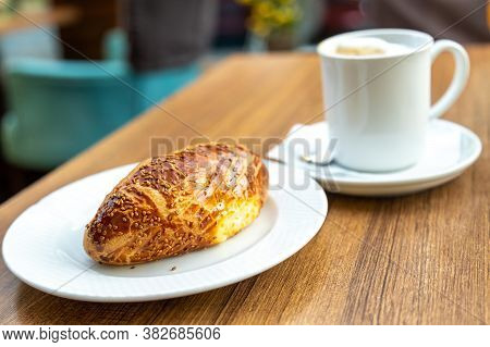 Sezam Bun With Coffee On The Cafe Table. Still Life Closeup Of The Fresh Bun With Cheese And Olives.