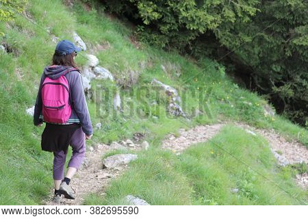 Young Woman With Backpack On Her Shoulders Walks On The Path In The Middle Of The Woods In The Mount