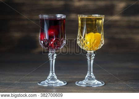 Homemade Tincture Of Red Cherry And Yellow Cherry Plum In A Wine Crystal Glasses On Wooden Backgroun