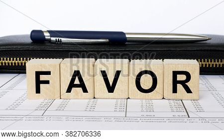 A Word Favor Written In A Wooden Cube With A Pen And Wallet