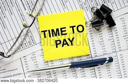 Text Time To Pay On Financial Tables With Pen, Glasses And Paper Clips