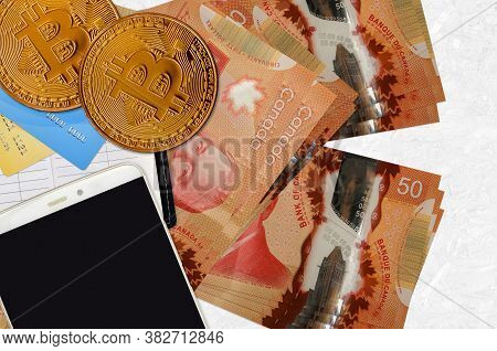 50 Canadian Dollars Bills And Golden Bitcoins With Smartphone And Credit Cards. Cryptocurrency Inves