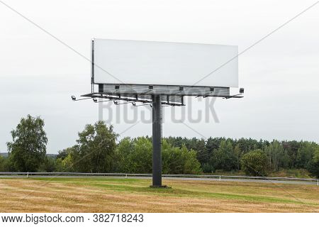 Large Commercial Megaboard, Billboard Standing In A Field Next To Road And Trees On A Skyline With E