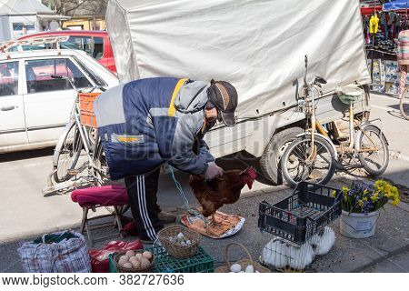 Sombor, Serbia - March 19, 2016: Senior Old Man Selling Farm Products, Food, On A Stall, Holding A L