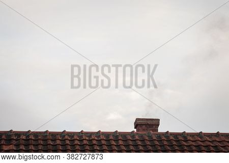 Brick Chimeny On The Roof Of An Individual Residential House With Tiles Exhausting Little Fumes At D