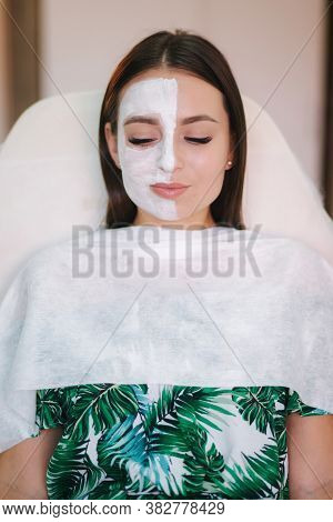 Beautiful Woman With White Mask On Hulf Of Face. Attractive Brunrtte Woman In Beauty Salon