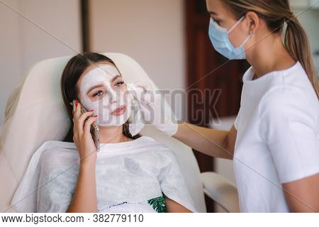 Hands Of Cosmetology Specialist Removing White Facial Mask Using Brush. Making Skin Hydrated And Fac
