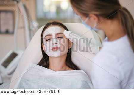 Hands Of Cosmetology Specialist Removing White Facial Mask Using Brush. Making Skin Hydrated And Fac
