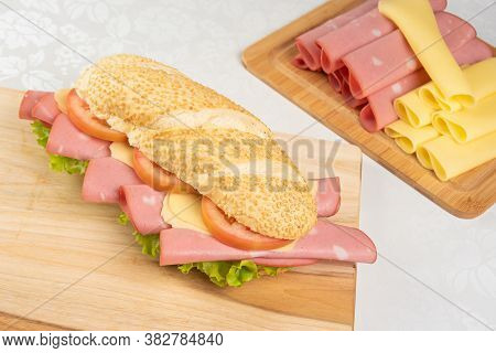 Mortadella Sandwich, Lettuce, Tomato And Cheese On A Polished Board And Slices Of Mortadella And Che