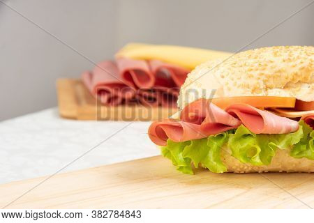 Mortadella Sandwich, Lettuce, Tomato And Cheese On A Polished Board And Slices Of Mortadella And Che