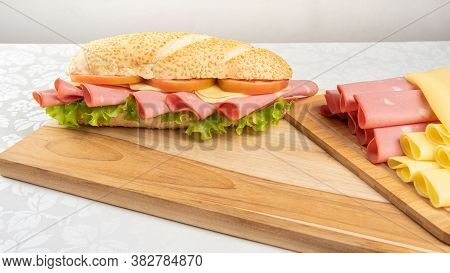 Mortadella Sandwich, Lettuce, Tomato And Cheese On A Polished Board And Slices Of Mortadella And Che