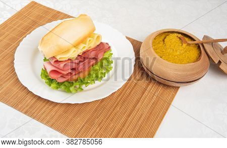 Mortadella And Lettuce Sandwich, On A White Plate And A Bamboo Mat And Pepper Sauce And Mustard On A