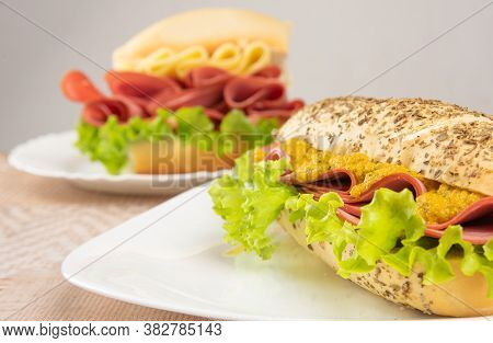 Mortadella, Lettuce And Cheese Sandwiches And Pepper And Mustard Sauce On White Plates On A Table Wi