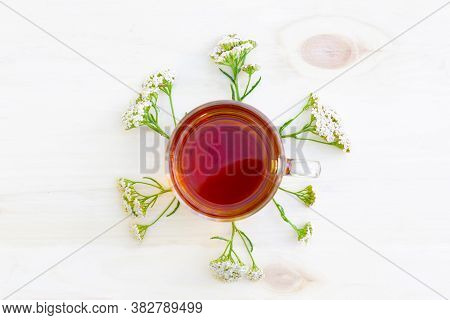 The Cup Of Black Herbal Tea With Branches Of Yarrow On Wooden Background. Top View.