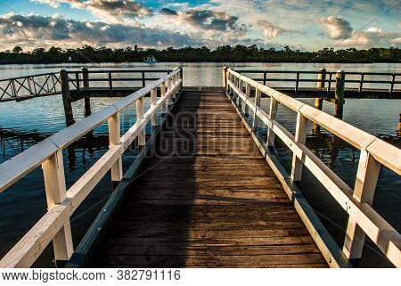 Wooden Jetty Into The Distance Over Water At Sunrise
