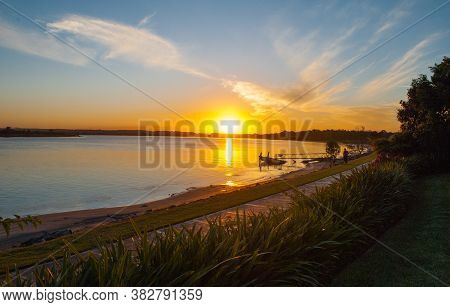 Sunrise In The Distance Reflecting Over Still Water