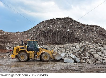 Front End Loader At Landfill For Disposal Of Construction Waste. Backhoe Digs Gravel And Concrete Cr