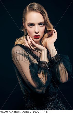Portrait of a beautiful woman in an elegant evening dress on a black background. Clothing, makeup and hairstyle in the style of the 1920s.