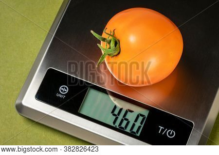 fresh yellow omato on a digital nutrition diet scale, healthy eating concept