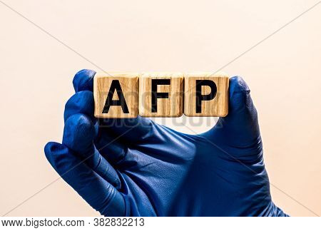 The Word Afp Which Is Made From Wooden Cubes. Hands In A Blue Glove. Isolated On White Background.