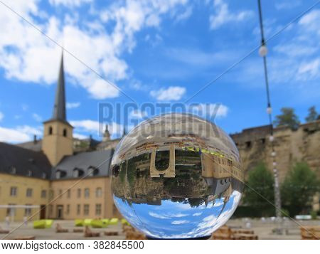 Neumunster Abbey And Palmyra Gate Copy In Luxembourg Grund Through Crystal Ball, Blurry Background, 