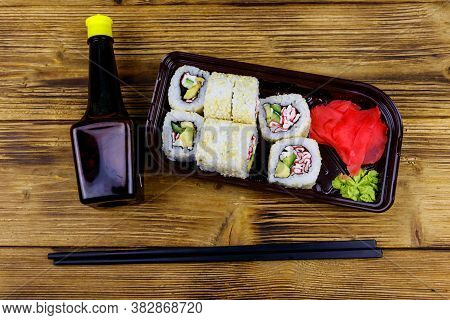 Uramaki Sushi Rolls With Surimi In Plastic Box On Wooden Table. Top View. Sushi For Take Away Or Del